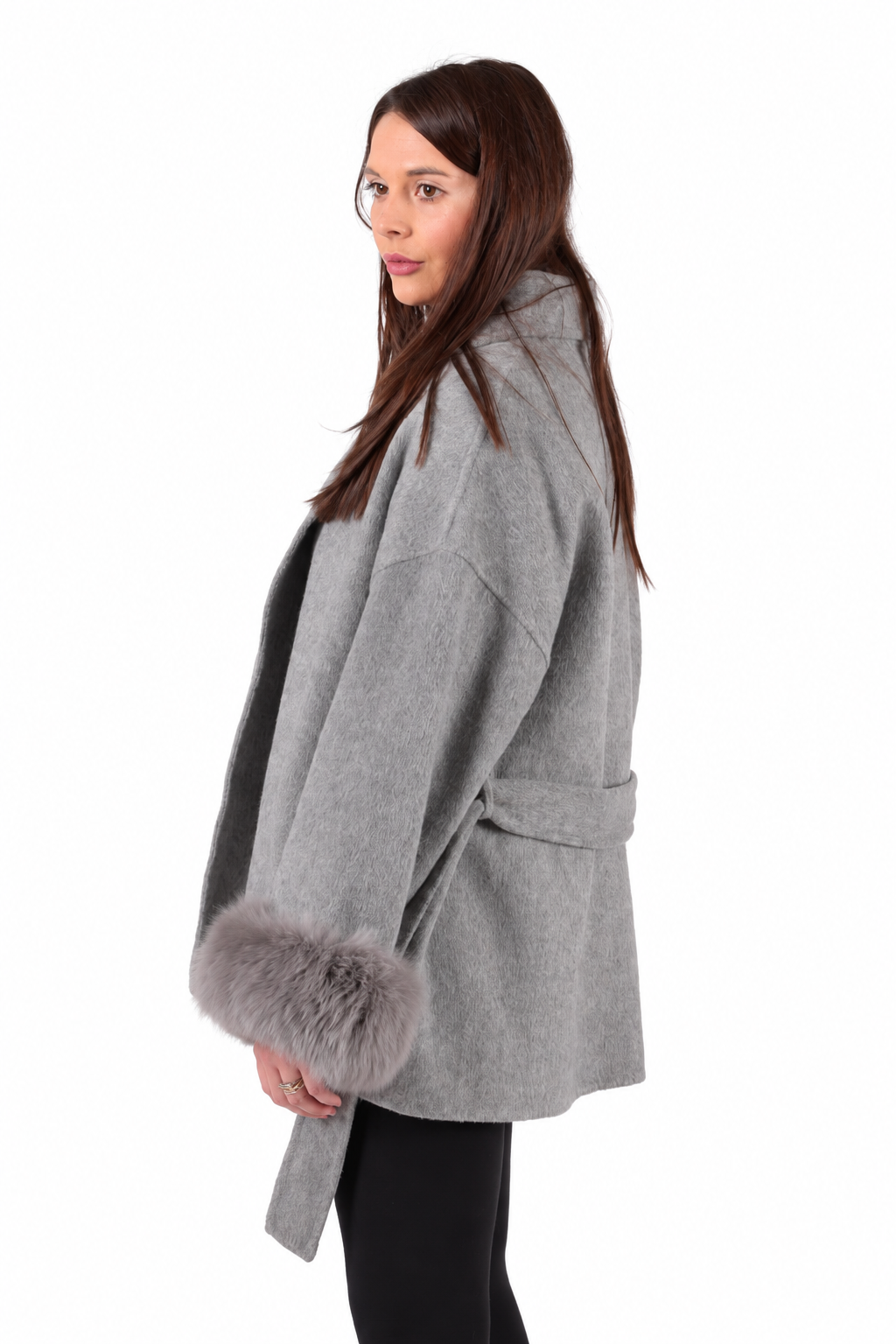 A woman wearing a light gray wool coat with a gray fox-fur trimmed hem, shown from a side-back angle against a plain white background.
